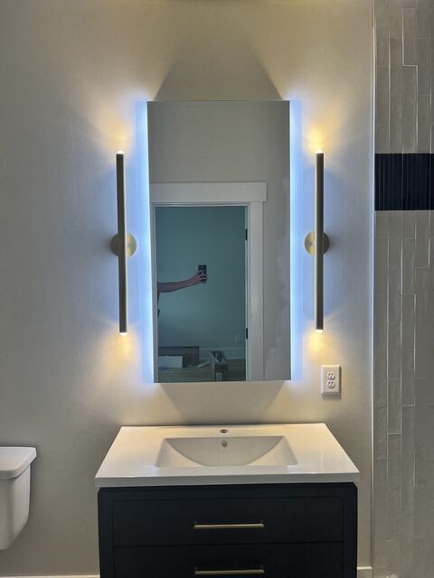 Backlit mirror with vertical sconces at a bathroom vanity
