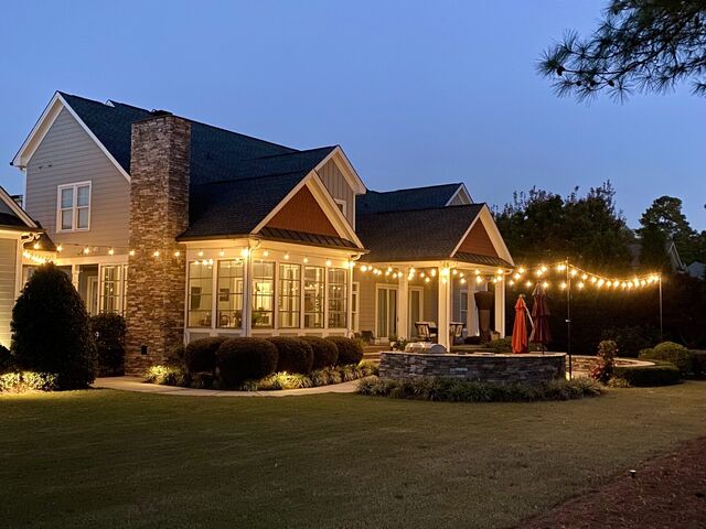 Bistro lights across a back porch and patio at dusk