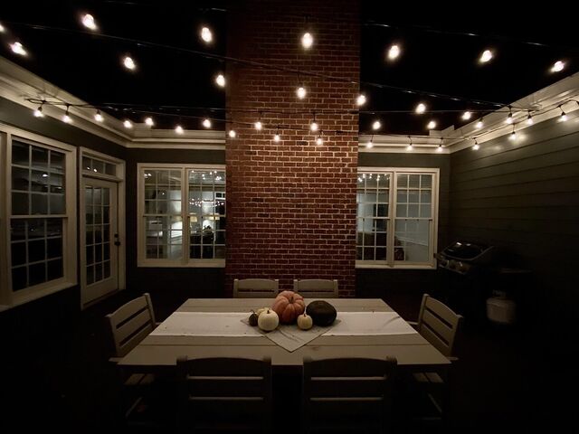 Bistro lights strung over a patio dining table