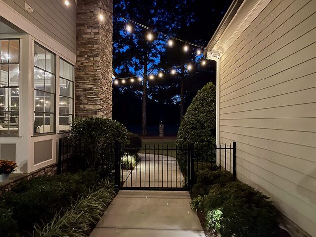Bistro lights over a side-yard path and gate