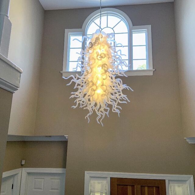 Sculptural blown-glass chandelier centered on a two-story foyer window