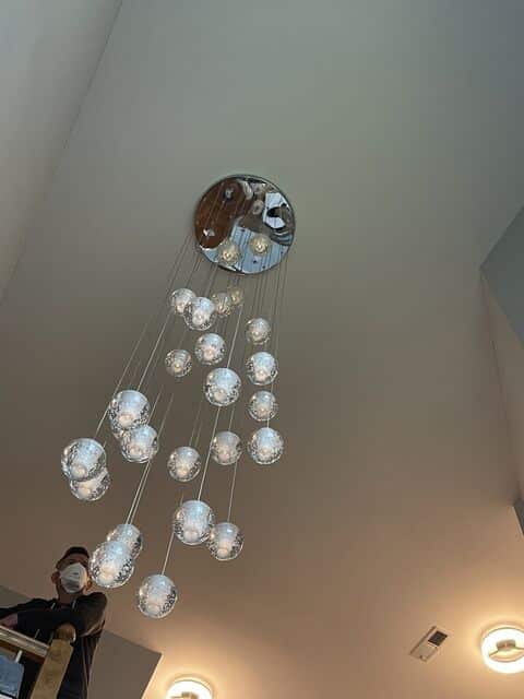 Cascading bubble-glass pendant cluster installed in a stairwell with a two-story window