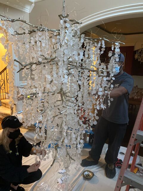 ARC electricians assembling a large crystal chandelier before lifting it into place