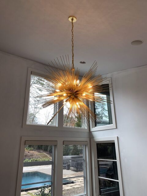 Gold sputnik chandelier installed in a two-story living room with a view to the pool