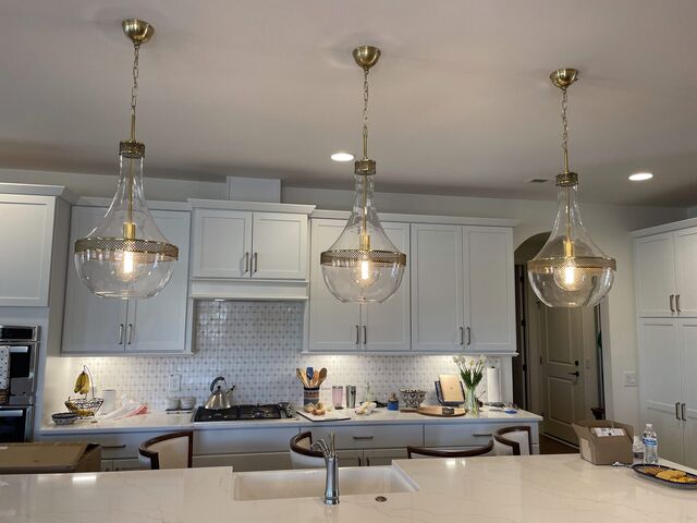 Glass island pendants with under-cabinet lighting in a white kitchen