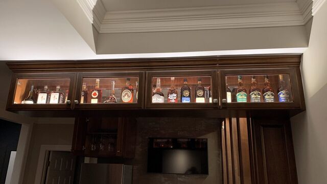 Lighted glass-front cabinets above a home bar