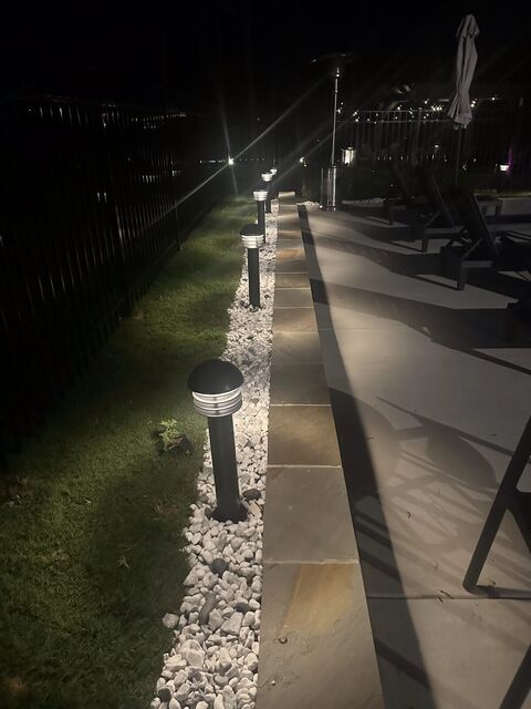 Path lights along a walkway beside a pool fence