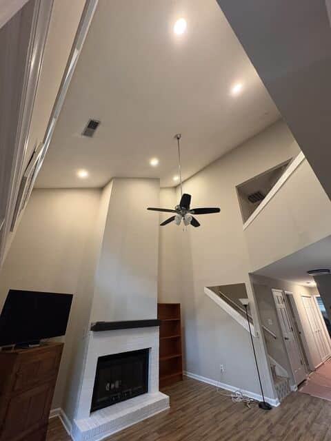 Recessed lighting and a ceiling fan in a tall living room